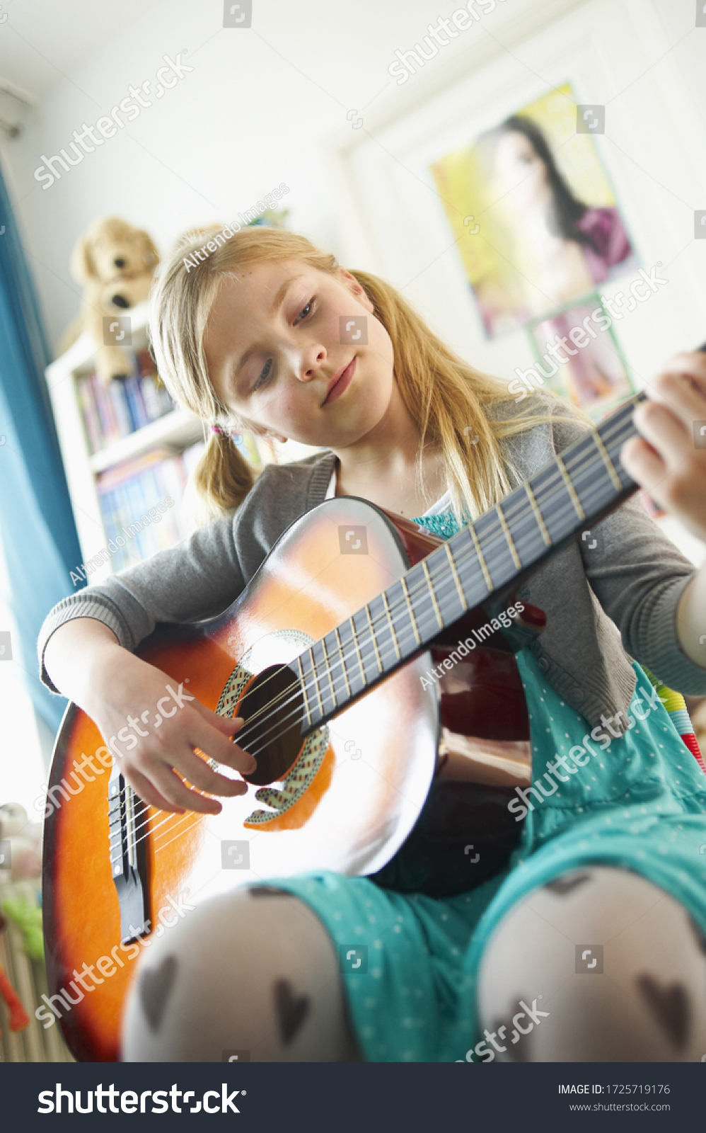 Young girl playing guitar in bedroom #1725719176