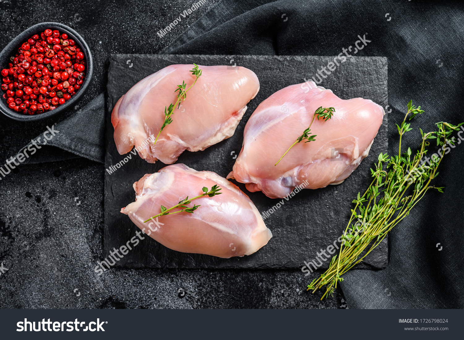 Raw boneless chicken thighs fillet. Black background. Top view #1726798024