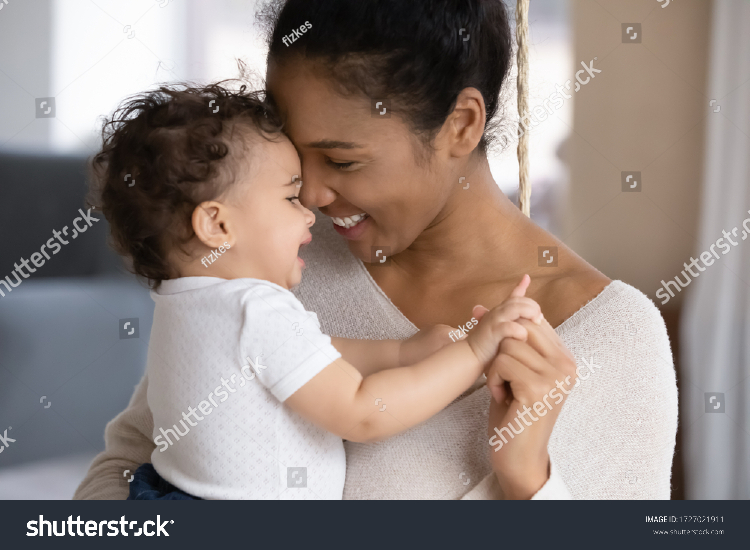 Close up of happy young african American mother hug cuddle little infant or toddler, loving smiling biracial mom embrace small baby child, enjoy tender family moment, motherhood, childcare concept #1727021911