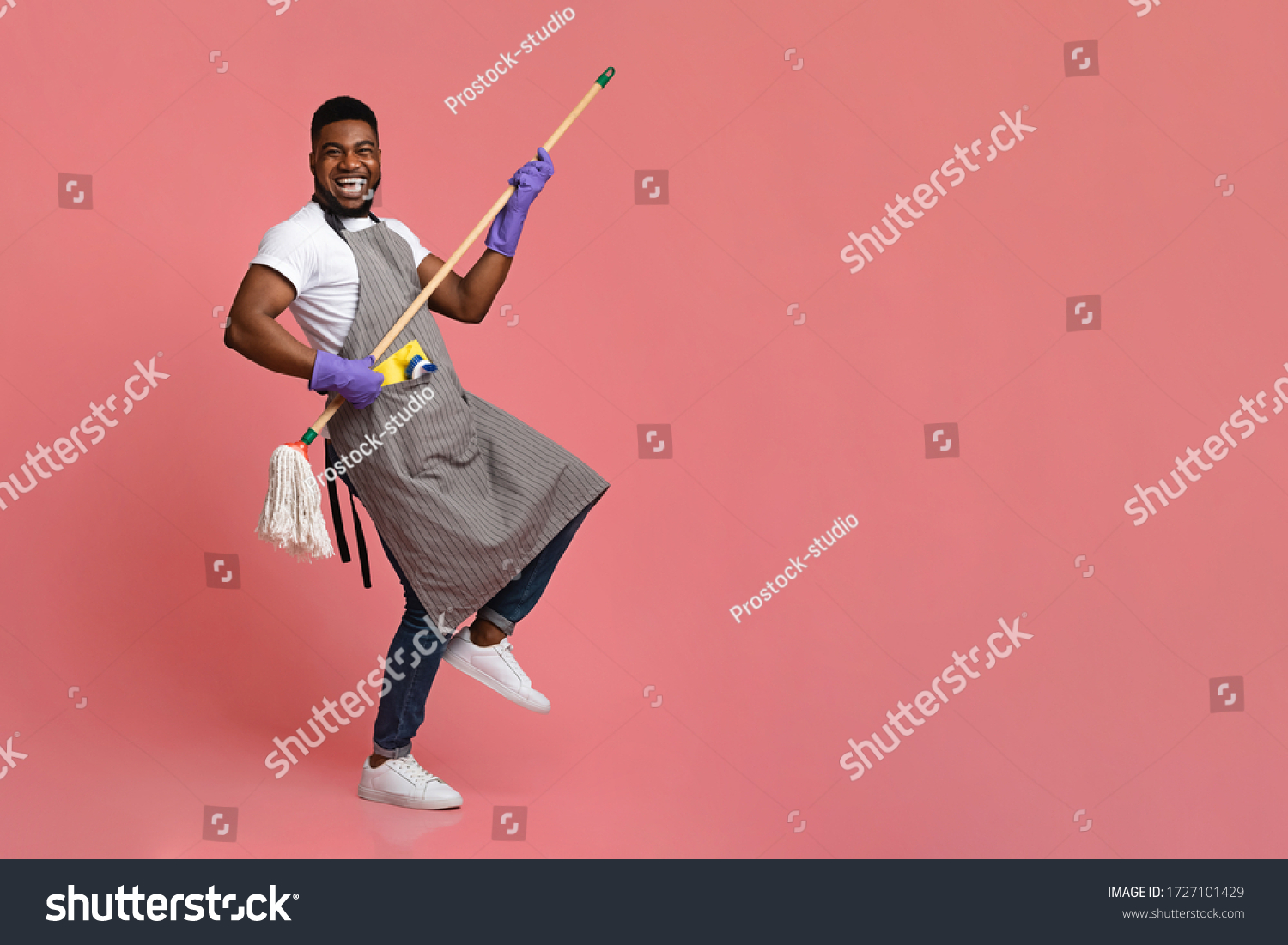 Funny African Man Using Mop Handle As Guitar, Having Fun During Cleaning. Posing Over Pink Background In Studio, Copy Space #1727101429