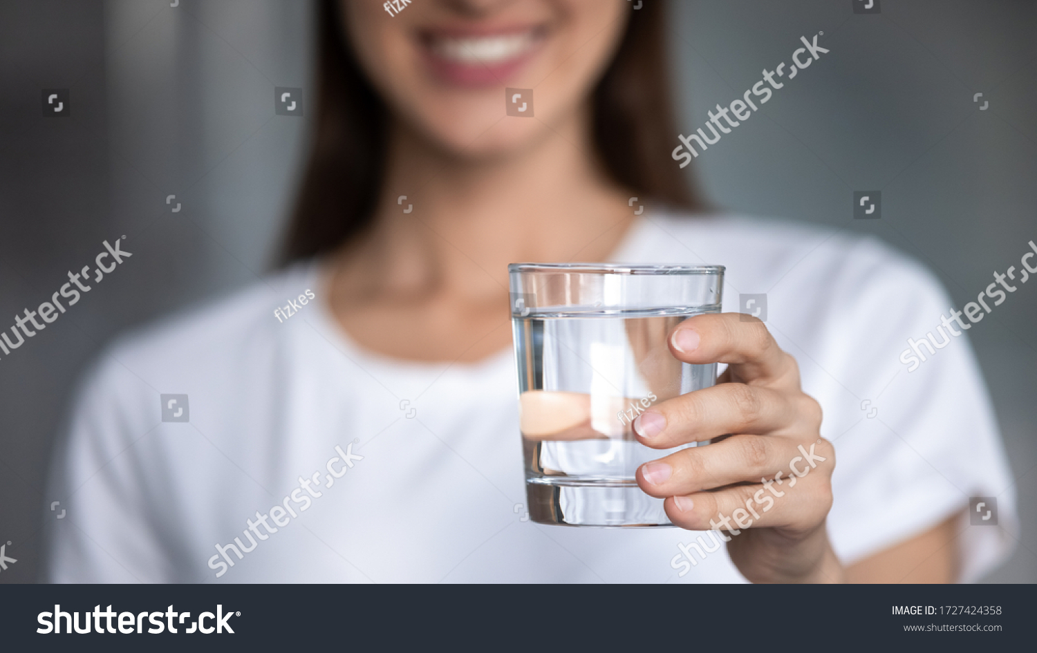 Horizontal banner image, on foreground caucasian female hand holds glass of clear water give to camera smiling selective close up focus. Concept of healthy lifestyle, beauty skin health care treatment #1727424358