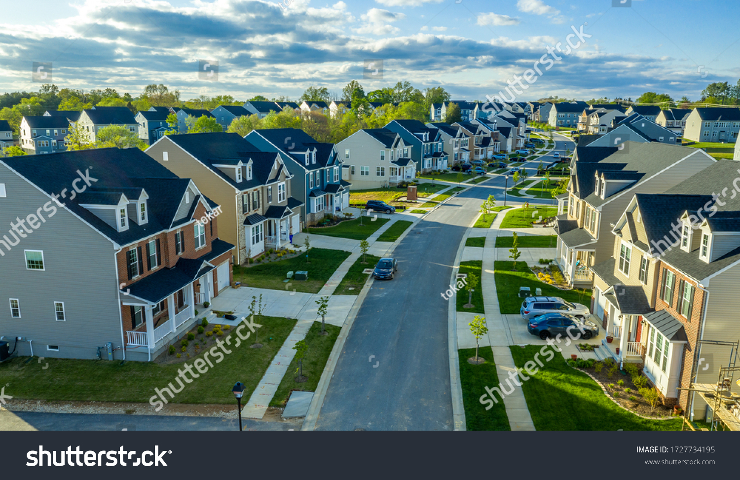 Aerial view of classic upper middle class neighborhood street with luxury single family homes with colorful siding for the up and coming with trees planted at equal distance in Maryland USA #1727734195
