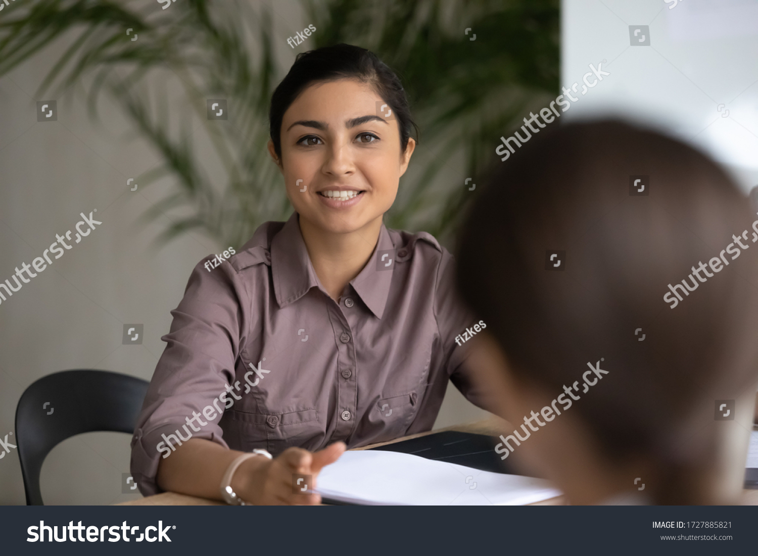 Close up happy young indian ethnic businesswoman talking about finance business project. Smiling diverse attractive female leader discussing sales presentation with workers in boardroom at meeting. #1727885821