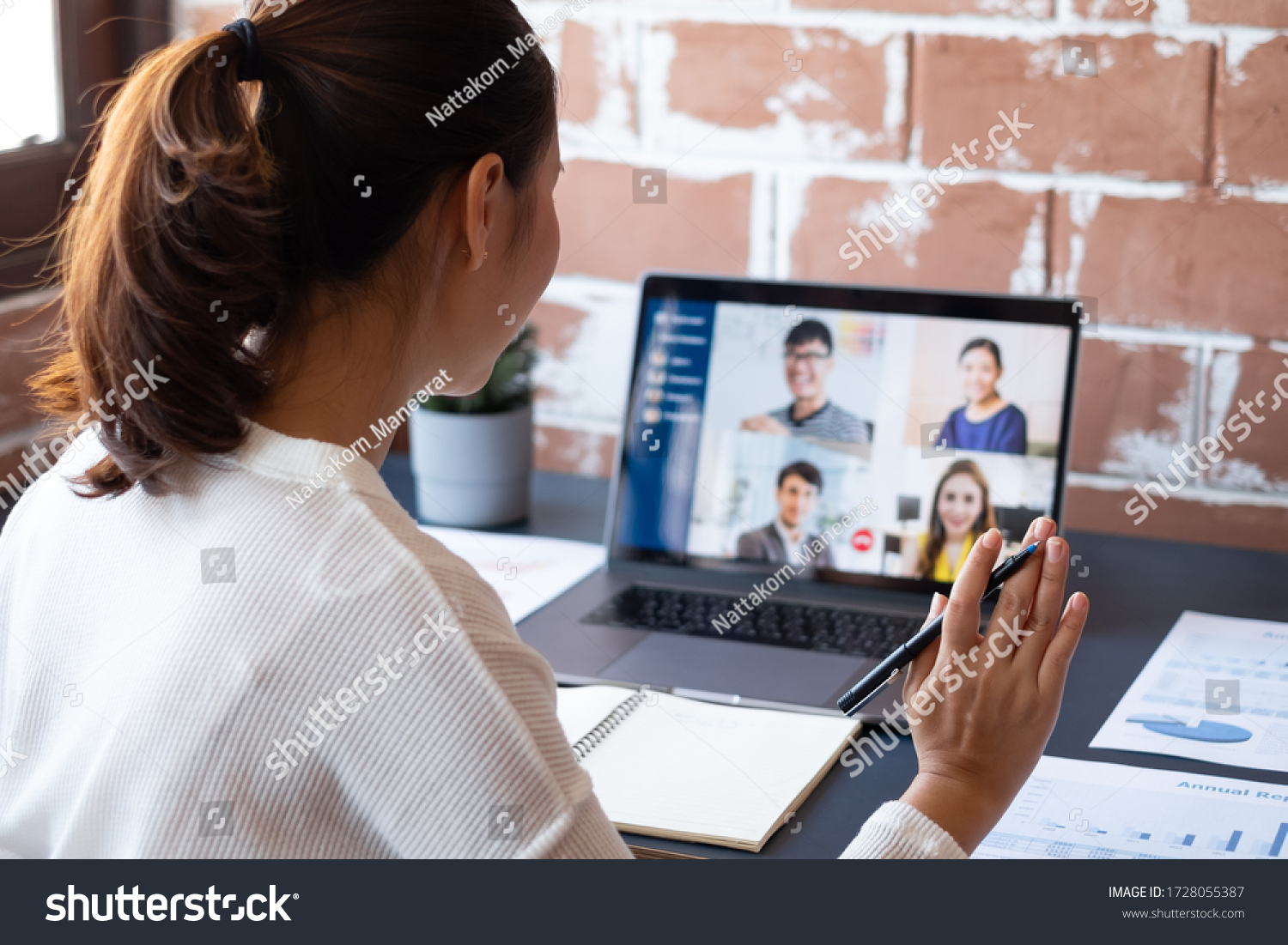 Young Asian businesswoman work at home and virtual video conference meeting with colleagues business people, online working, video call due to social distancing at home office #1728055387