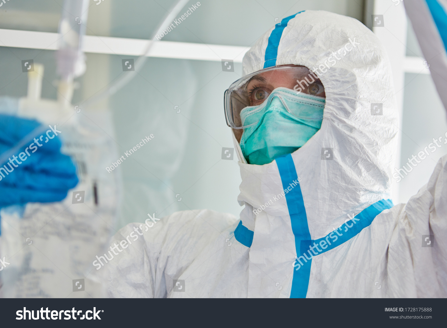 Doctor in protective clothing in hospital intensive care unit treats Covid-19 patient with infusion during coronavirus pandemic #1728175888