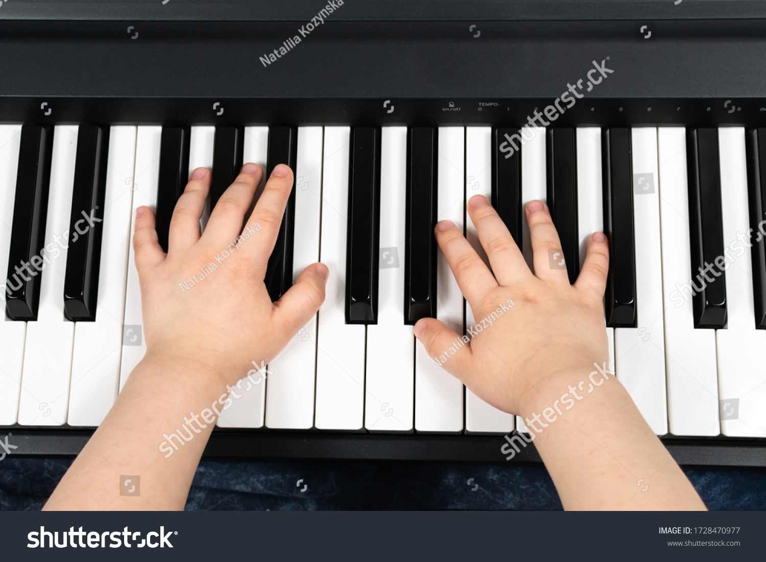 Hands of a young child playing the piano. Learning to play the piano. Studying at home. To stay home. View from above. #1728470977