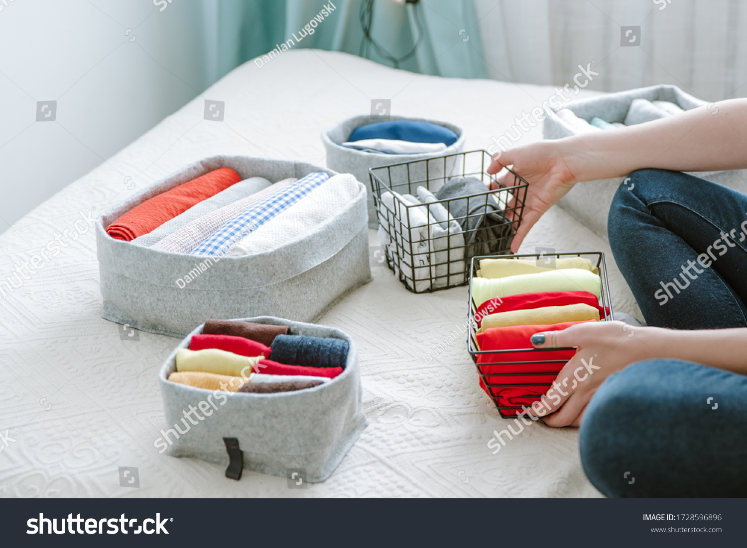 Folding clothes and organizing stuff in boxes and baskets. Concept of tidiness, minimalism lifestyle and japanese t-shirt folding system. Minimalist storage system and wardrobe #1728596896