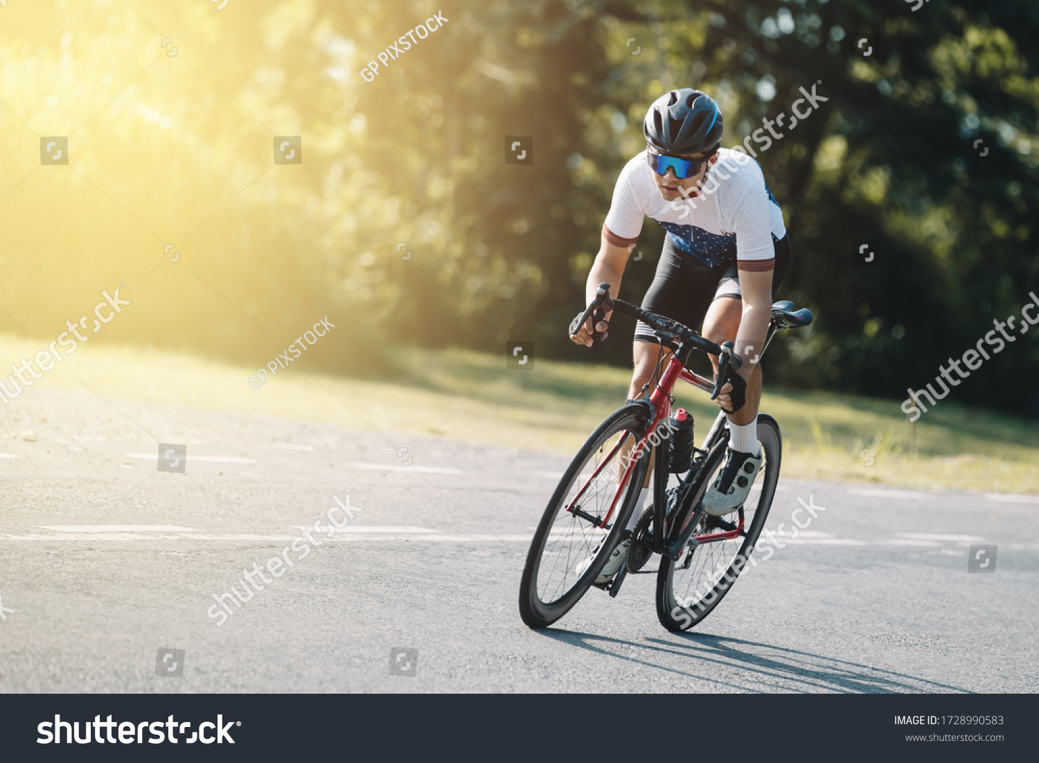 Cyclist pedaling on a racing bike outdoors in sun set .The image of cyclist in motion on the background in the evening. #1728990583