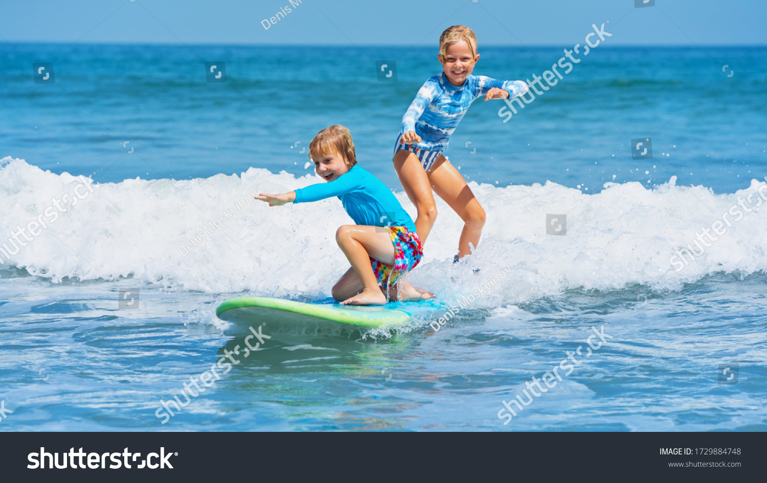 Happy baby boy and girl - young surfers ride with fun on one surfboard. Active family lifestyle, kids outdoor water sport lessons, swimming activity in surf camp. Sea beach summer holiday with child. #1729884748
