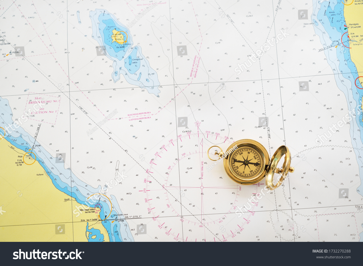 Retro styled golden compass (sundial) and old white nautical chart close-up. Vintage still life. Sailing accessories. Travel and navigation theme #1732270288