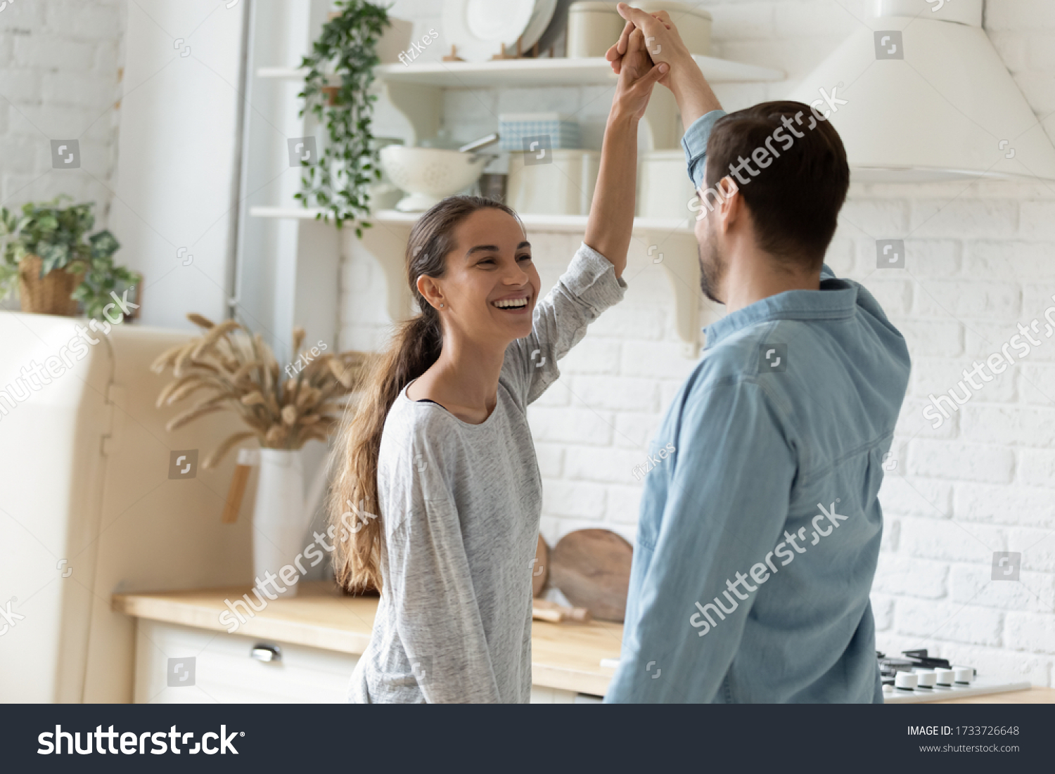 Overjoyed millennial husband and wife dancing in modern kitchen celebrate wedding anniversary at home together, happy young couple tenants have fun enjoy family weekend in new own house or apartment #1733726648
