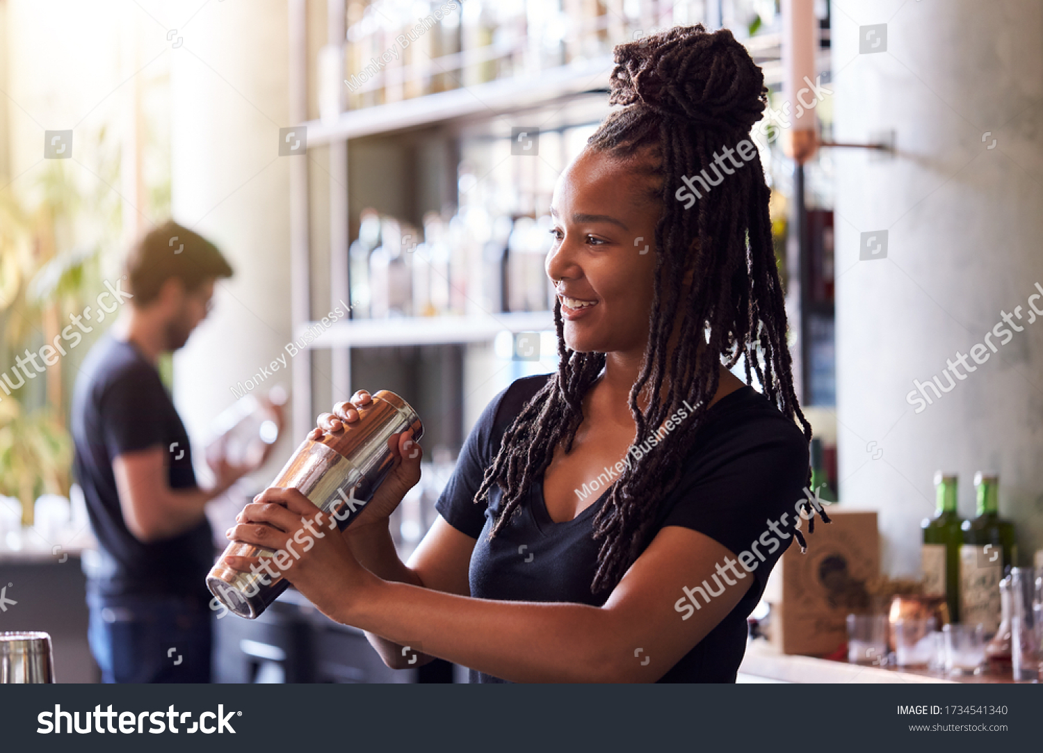 Female Bartender Mixing Cocktail In Shaker Behind Bar #1734541340