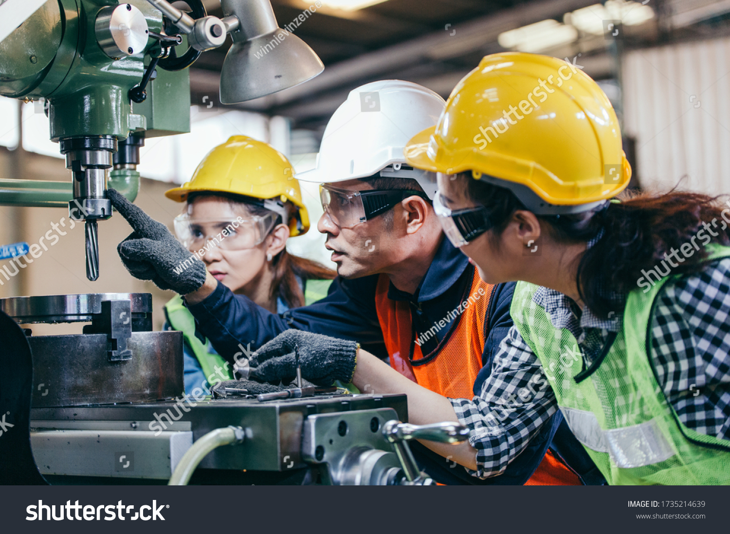 Asian male foreman manager showing case study of factory machine to two engineer trainee young woman in protective uniform. teamwork people training and working in industrial manufacturing business #1735214639