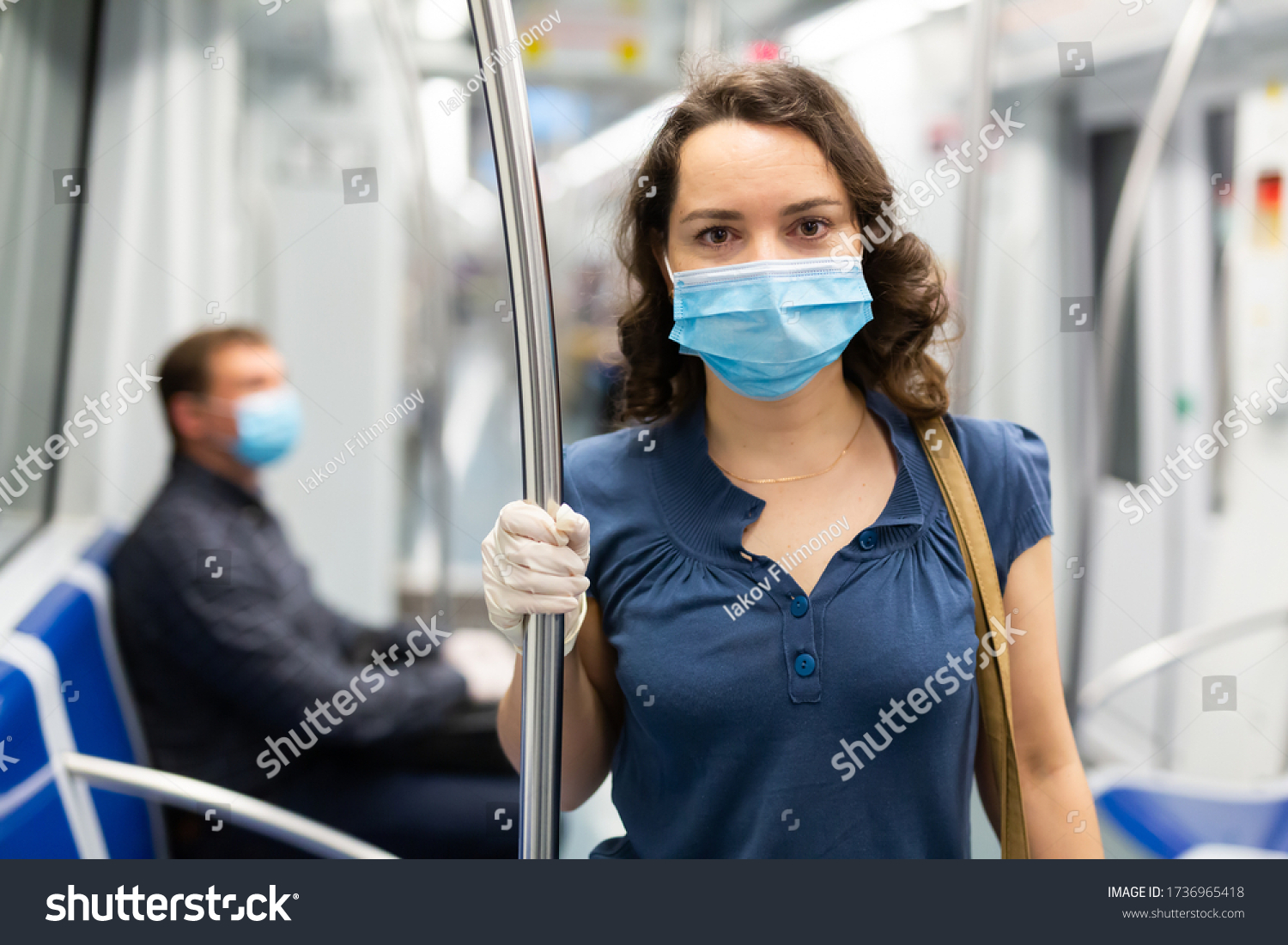 Portrait of focused woman in disposable mask and gloves traveling in subway train during daily commute to work in spring day. Concept of new life reality and precautions in COVID 19 pandemic #1736965418