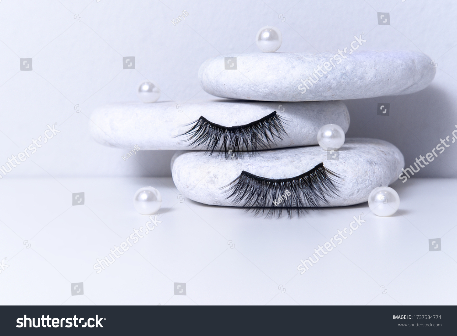 Magnetic fake artificial eyelashes and pearl on white stones. Home eyelash extension, cosmetology tool concept, beauty treatment, improving physical appearance #1737584774
