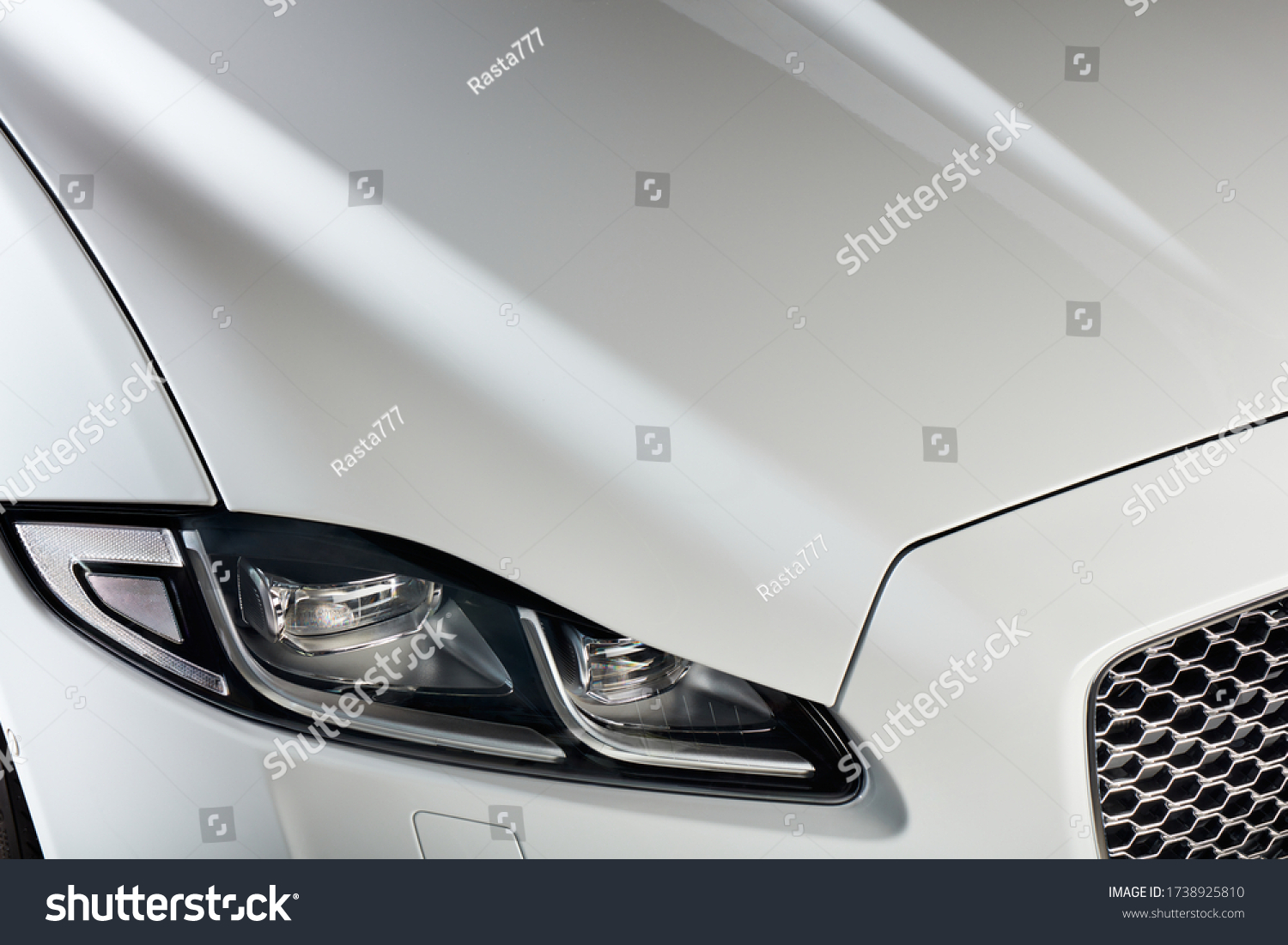 The headlight and bonnet of a white car. A modern and luxurious car. #1738925810