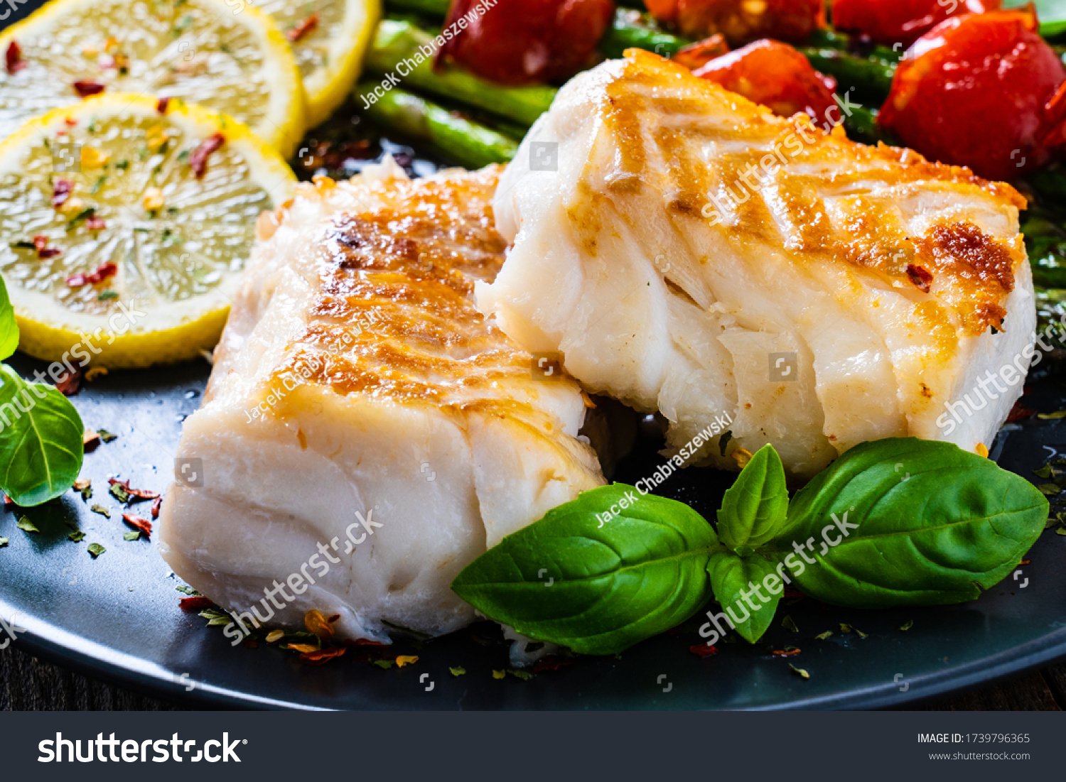Fish dish - fried cod fillet with asparagus on wooden table  #1739796365