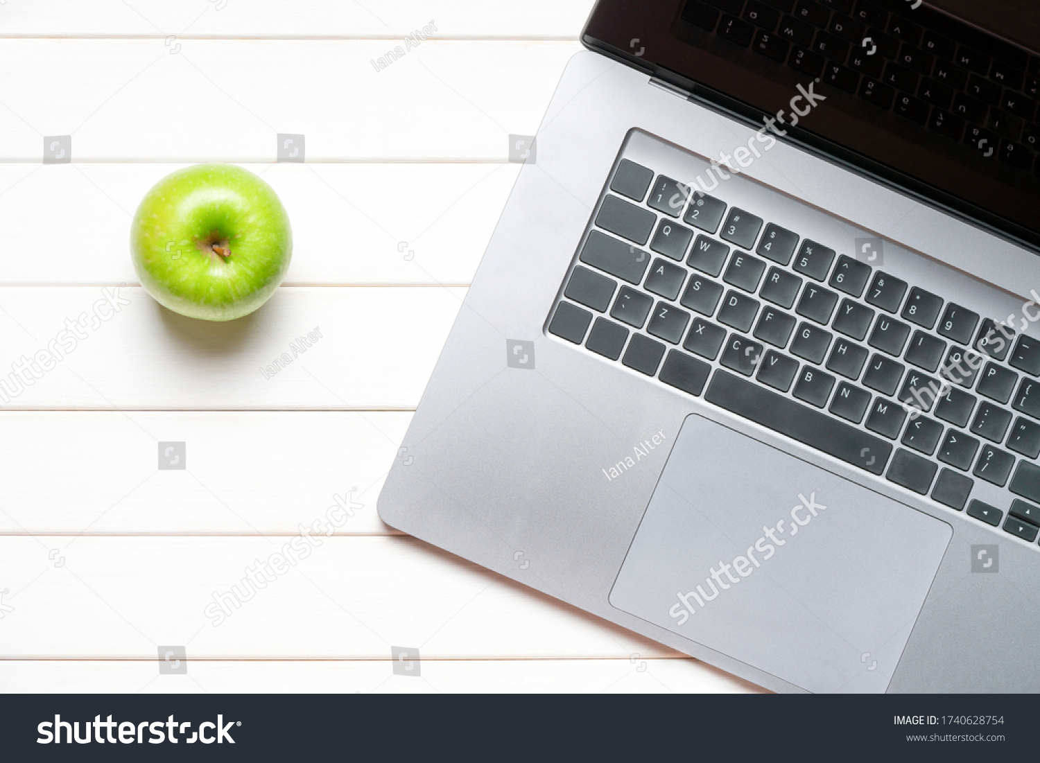 Laptop keyboard and green apple on white wooden table. Top view. Concept distance learning #1740628754