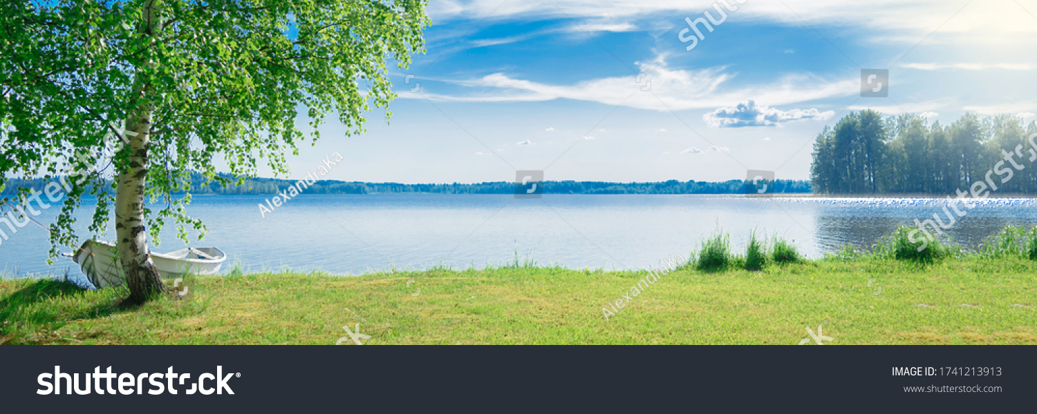 The beautiful landscape of a white simple wooden boat tied to a birch tree on the lake somewhere in the depths of Finland. Good summer day in nature. Concept vacation on the lake. Banner. #1741213913