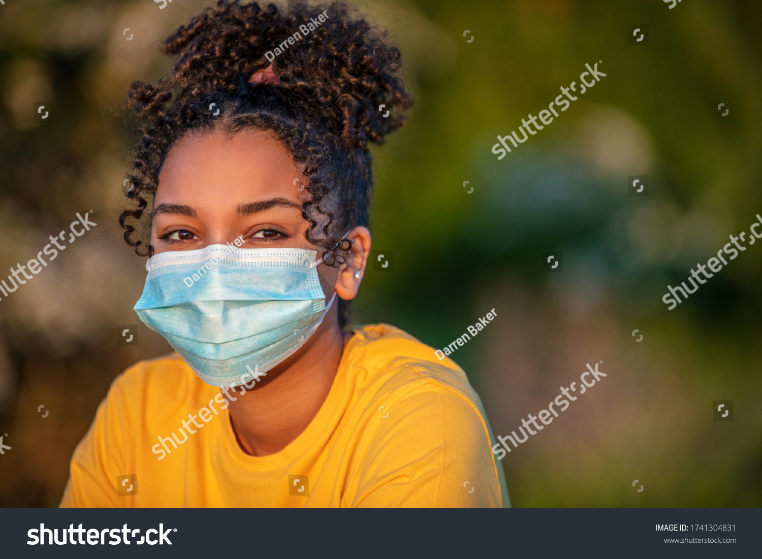 Mixed race African American teenager teen girl young woman wearing a face mask outside during the Coronavirus COVID-19 virus pandemic #1741304831
