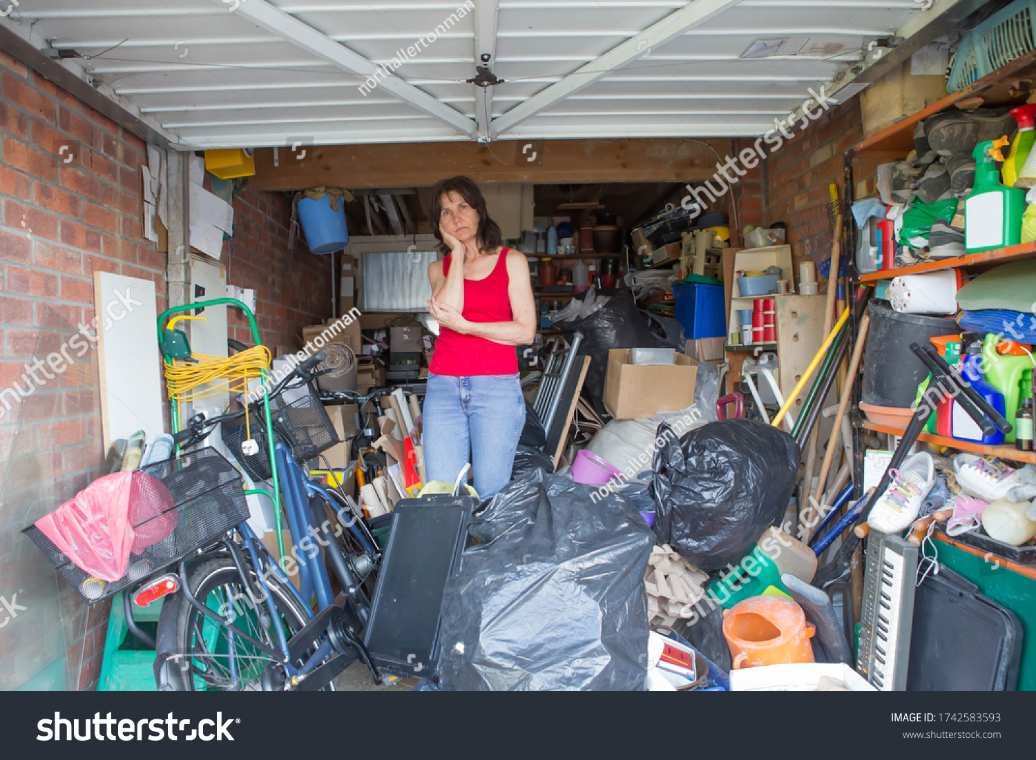 Woman looking bemused about where to start in clearing out her garage #1742583593