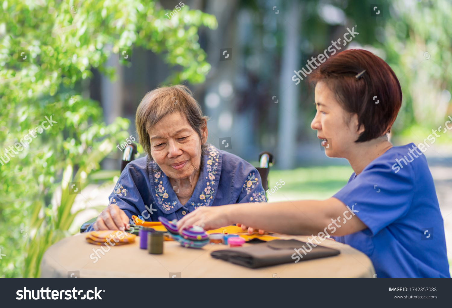 Elderly woman with caregiver in the needle crafts occupational therapy  for Alzheimer’s or dementia #1742857088