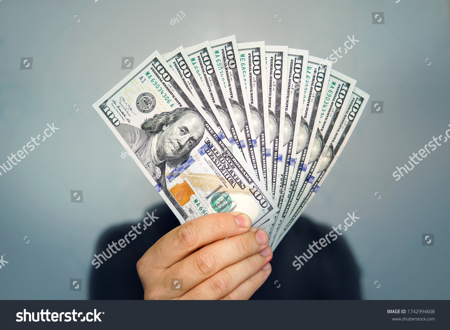 Hands holding dollar cash. 1000 dollars in 100 bills in a man's hand close-up on a dark background. #1742994608