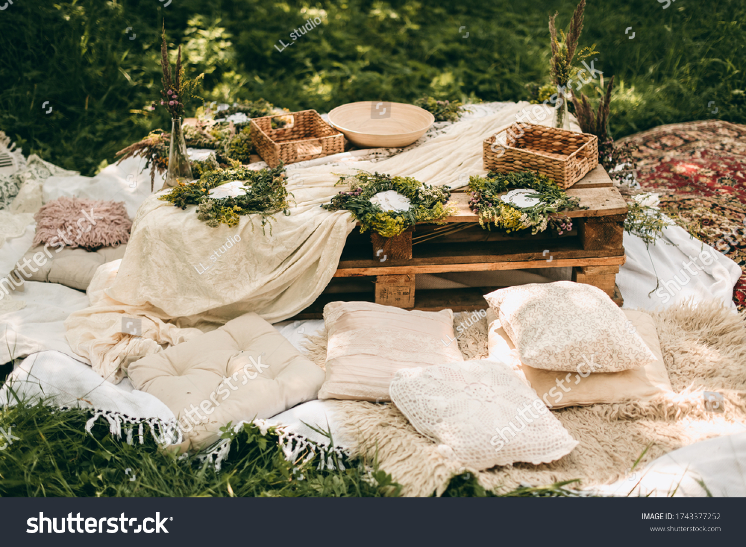 Beautiful white decor in boho style. Picnic in nature, table, carpets, wigwam, tent, pillows in the park. Celebration after quarantine. #1743377252