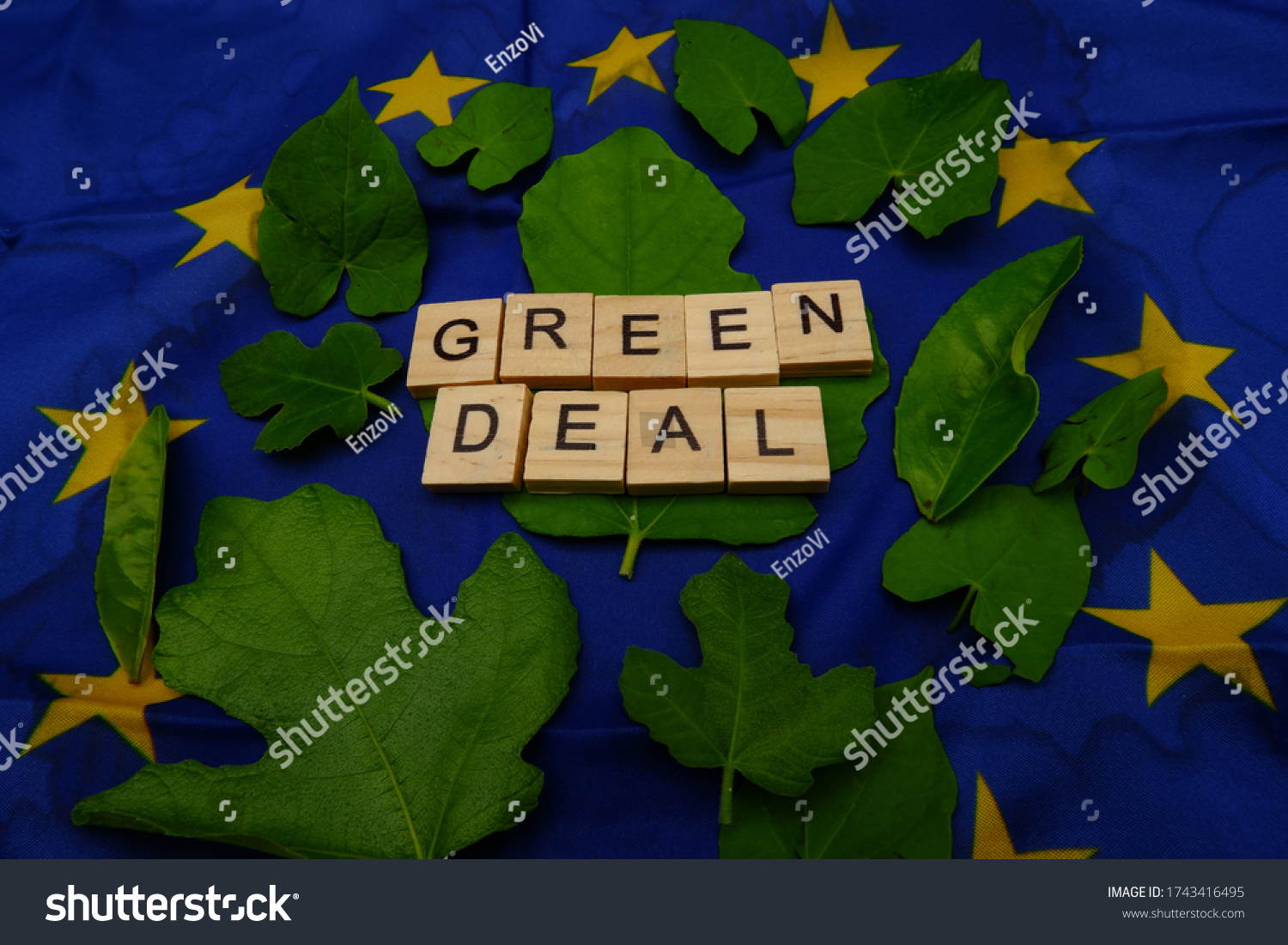 Some leaves,with a wooden inscription,green deal,above a European flag. Concept of fighting climate change on earth  #1743416495