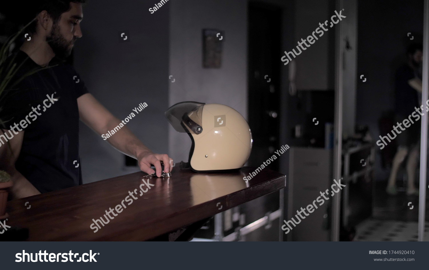 On the bar is a motorcycle helmet and keys. Biker takes a motorcycle helmet and keys for a motorcycle from a bar counter and sets off on a journey. #1744920410