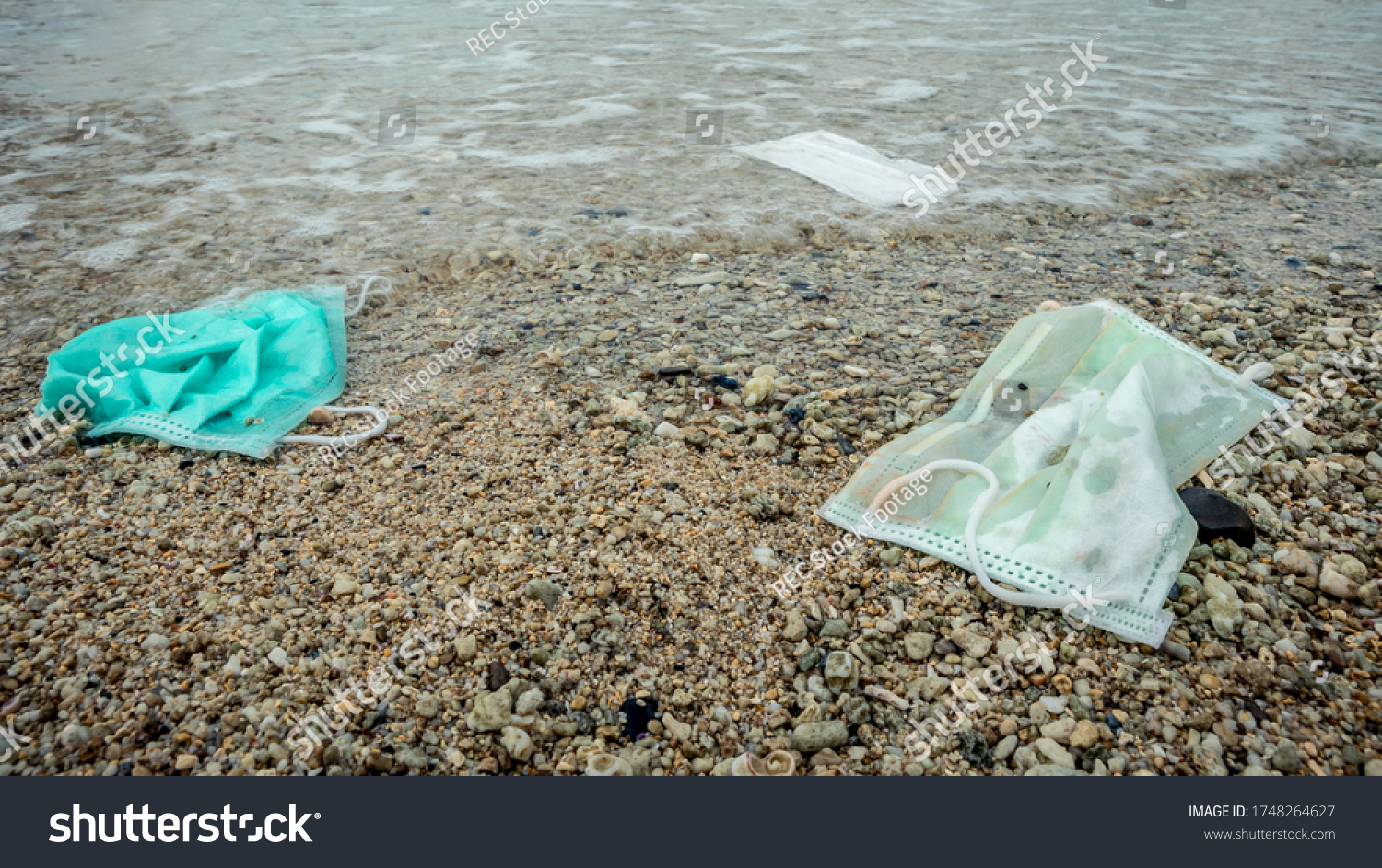 Waste during COVID-19. Discarded to ocean coronavirus single-use face masks. Environmental and coast plastic pollution. Trash in the beach threatening the health of oceans. #1748264627