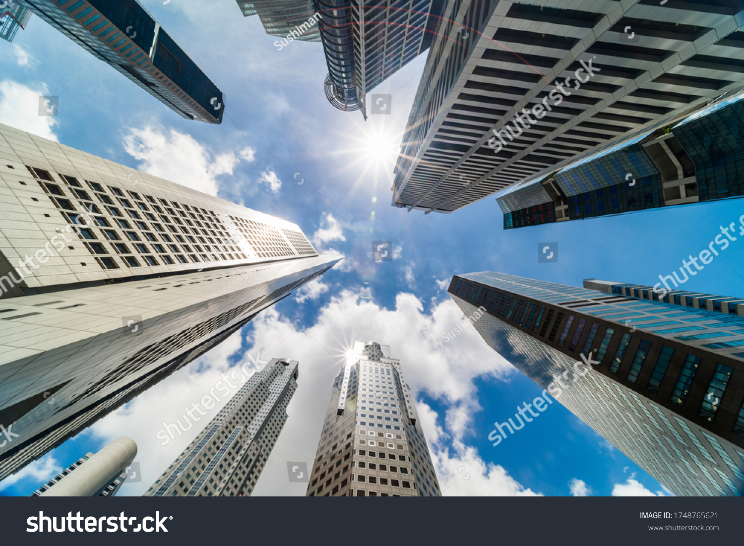 Skyscraper tower buildings in business district, Singapore city. Cloud and sun flares on sunny day sky. Low angle view. Asia financial economy, merger & acquisition, or modern architecture concept #1748765621