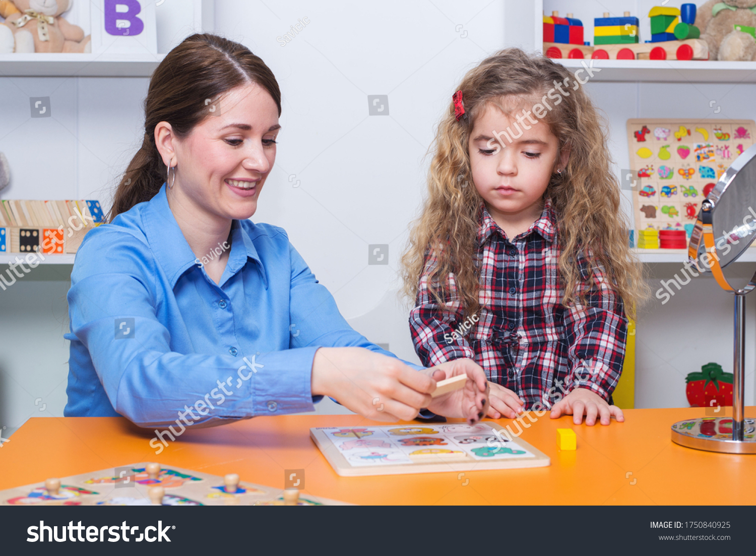Toddler girl in child occupational therapy session doing sensory playful exercises with her therapist. #1750840925