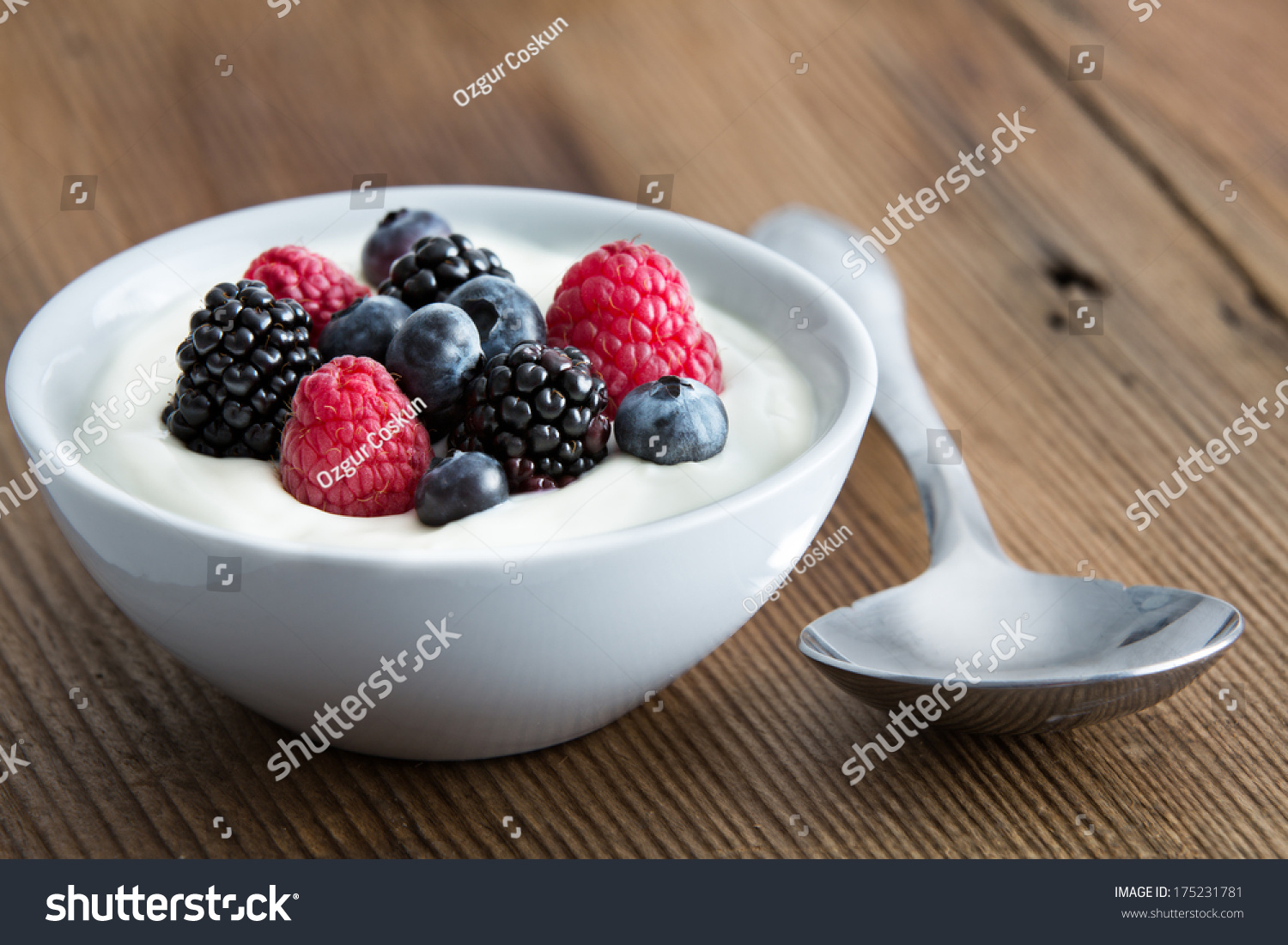 Bowl of fresh mixed berries and yogurt with farm fresh strawberries, blackberries and blueberries served on a wooden table #175231781