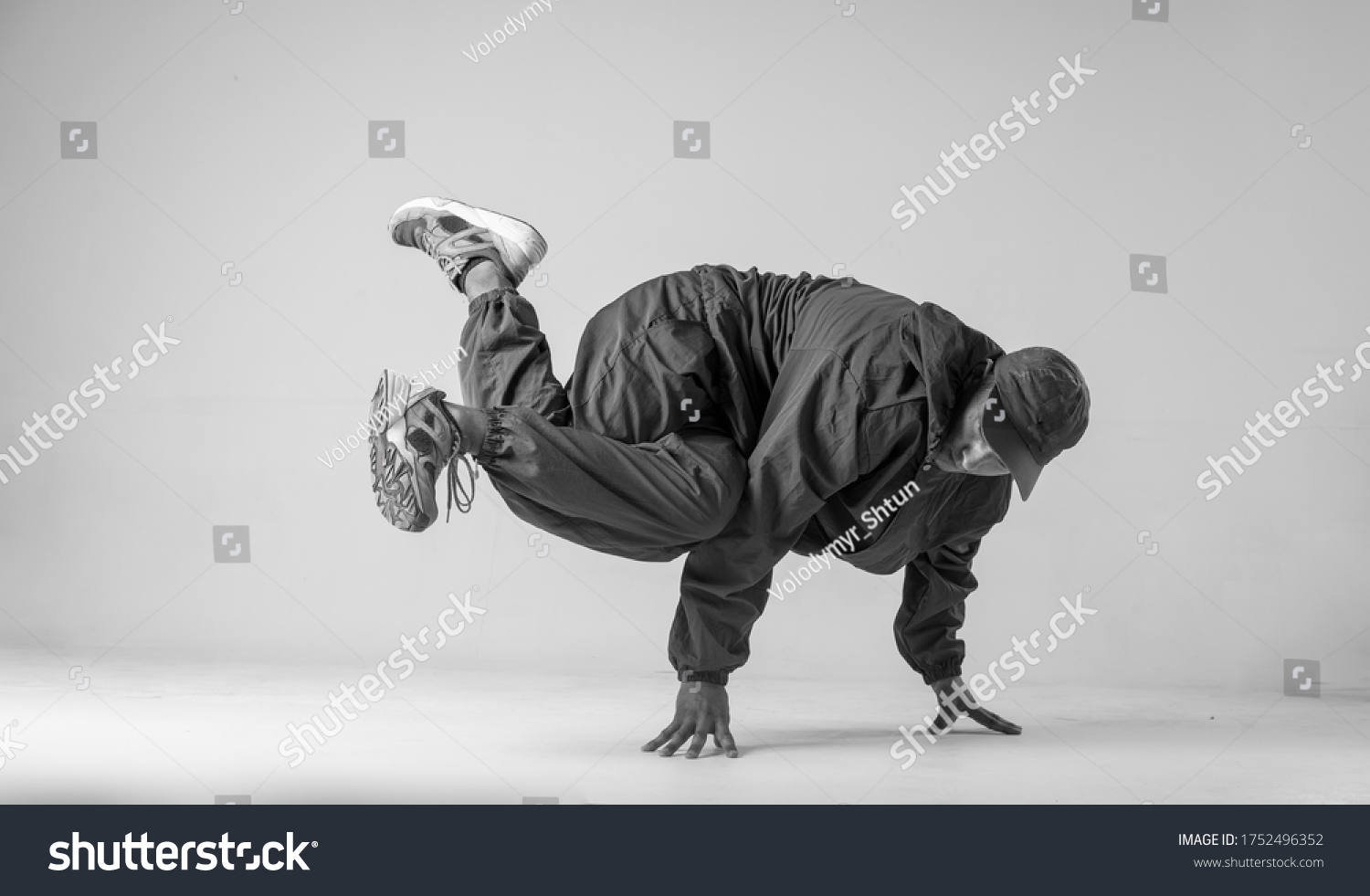 A man hip hop dancer or bboy freezes in one pose on a white background. Bboy doing stylish stunts. #1752496352