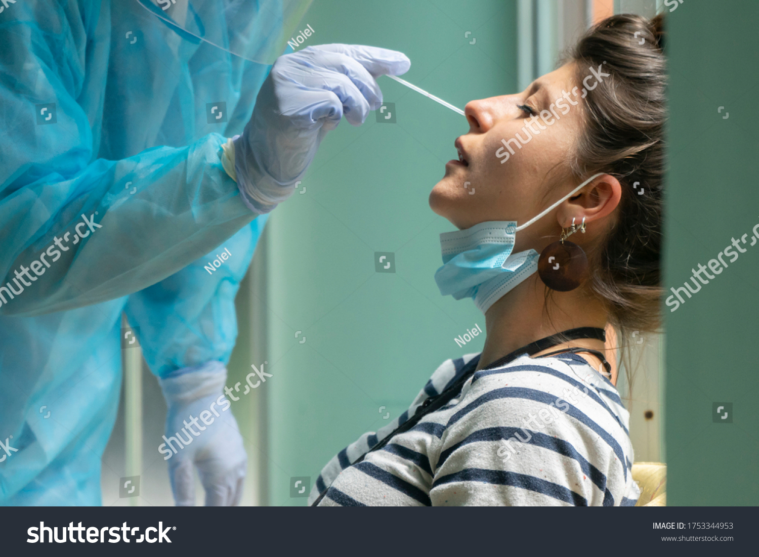 Healthcare worker with protective equipment performs coronavirus swab on Caucasian girl.Nose swab for Covid-19. #1753344953