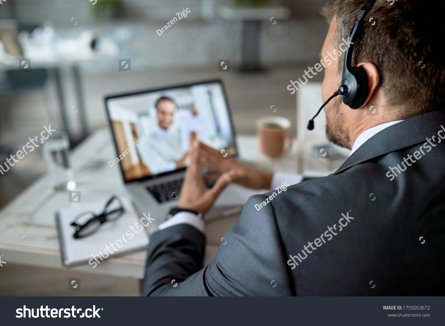Close-up of entrepreneur using laptop while having online business meeting in the office.  #1755053672