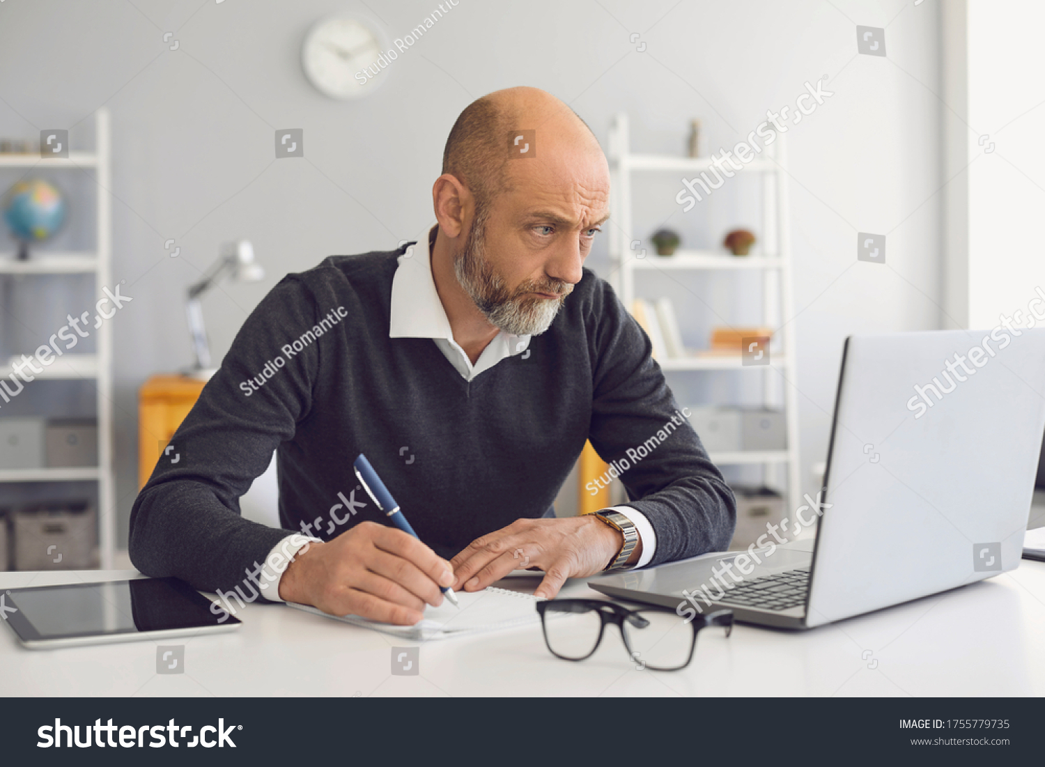 Work at home online. A senior man with a gray beard has a job in a laptop at home. #1755779735