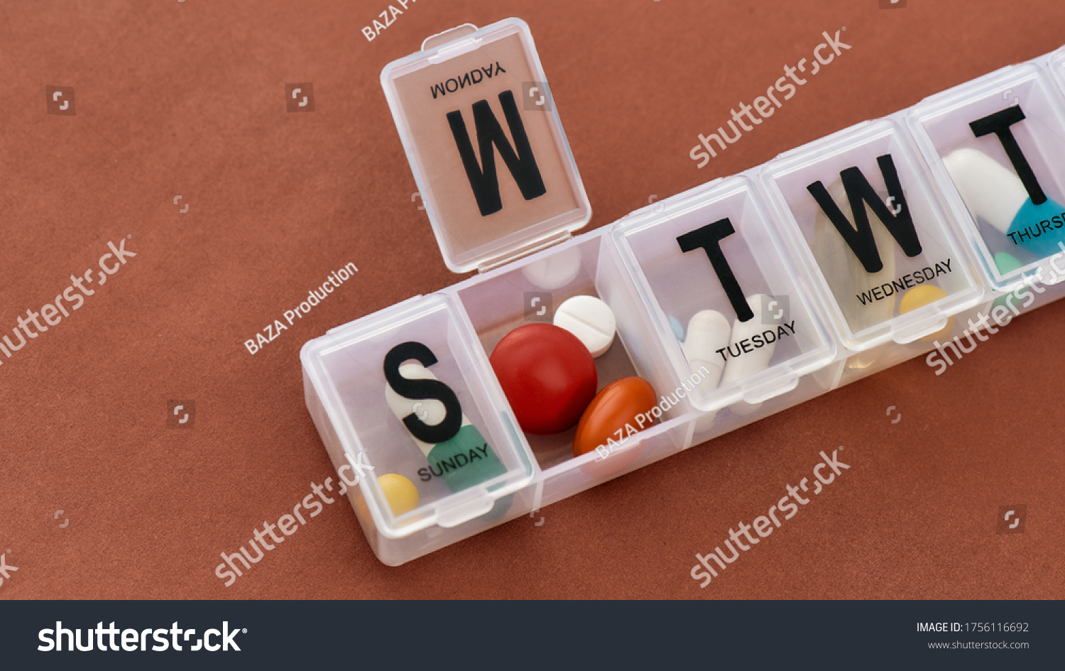 A weekly medicine dispenser opened for Monday, prescription pills and vitamins in a white pill box on terracotta background. Health care, vitamins and treatment concept. Horizontal shot #1756116692