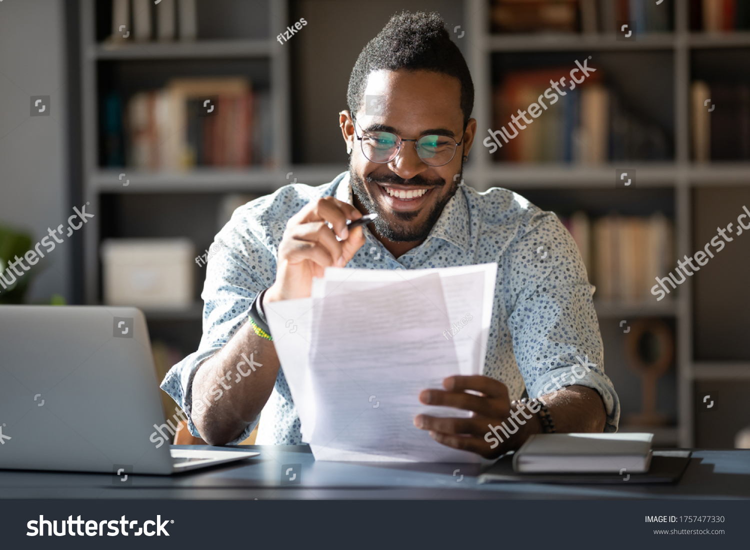 African student guy sitting at desk holding papers printed tasks perform test prepares for entrance exams enjoy process of study. Teacher checking assignment homework, company lawyer paperwork concept #1757477330