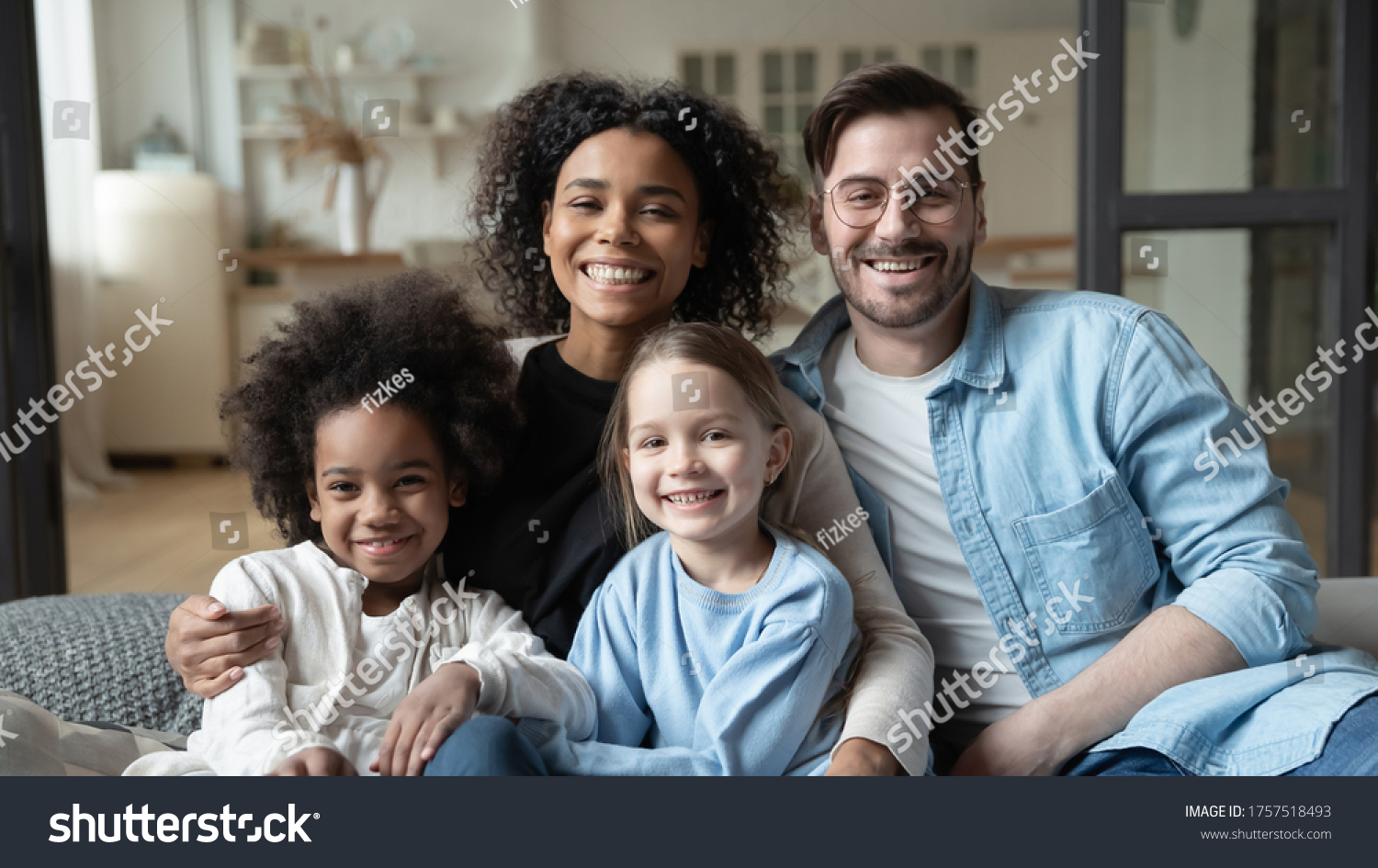 Multinational family married couple and daughters sit on couch looks at camera photo shooting feels happy. Cute multi-ethnic girls and parents portrait, homeowners, new home, prosperous future concept #1757518493