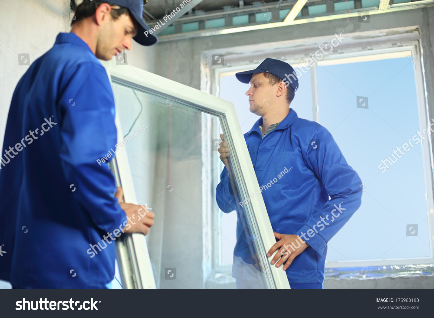 Two workers in blue work clothes set a new window in the window frame #175988183