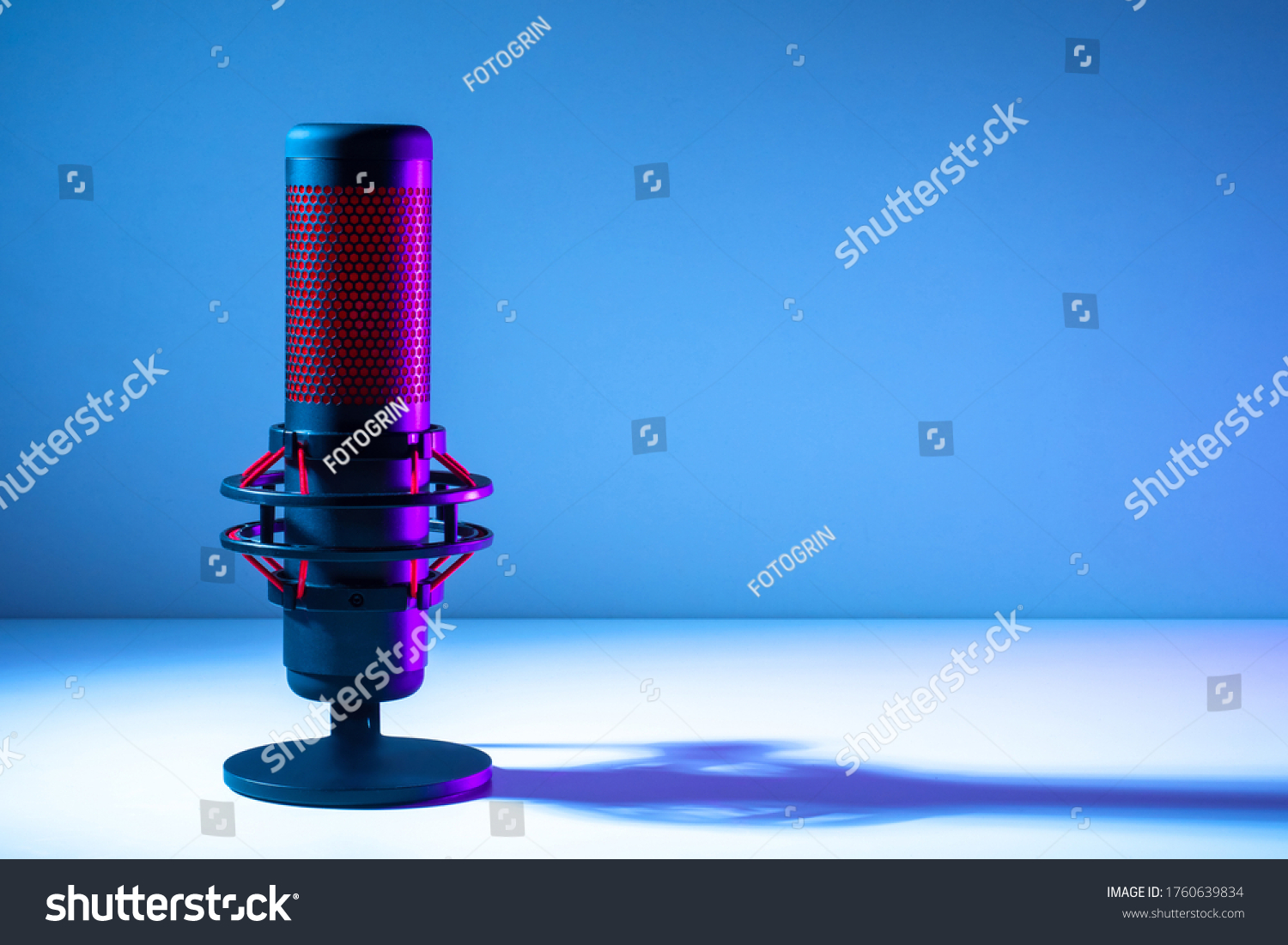 Microphone on a blue background. Space for text. Public speech. Sound amplification. Sound technology. Black and red microphone close-up. #1760639834