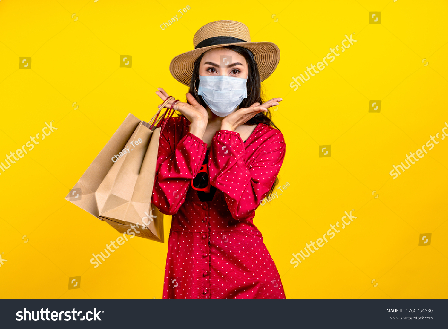 Portrait of young happy carefree asian woman wear hat and facemask carrying shop bag smile on isolated color background in concept back to shopping, new normal summer fashion lifestyle after covid19. #1760754530