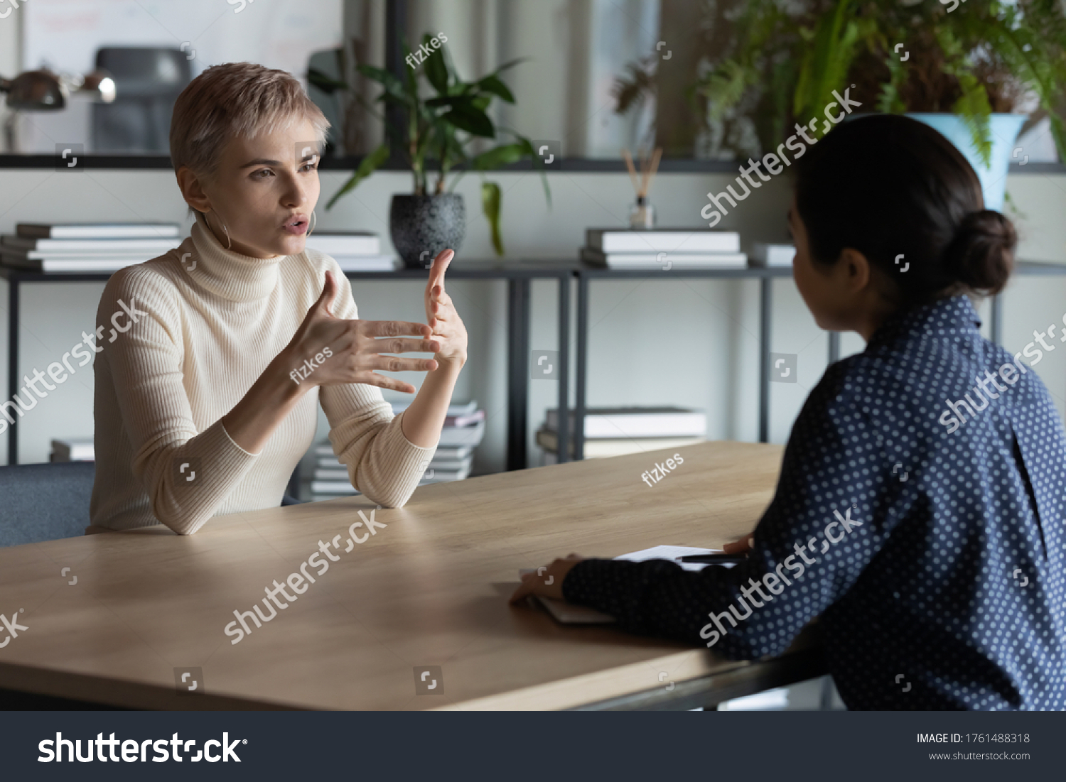 Diverse business women sit in front of each other conduct business conversation. Job interview applicant and headhunter talk. Company representative make offer to client convince buy services concept #1761488318