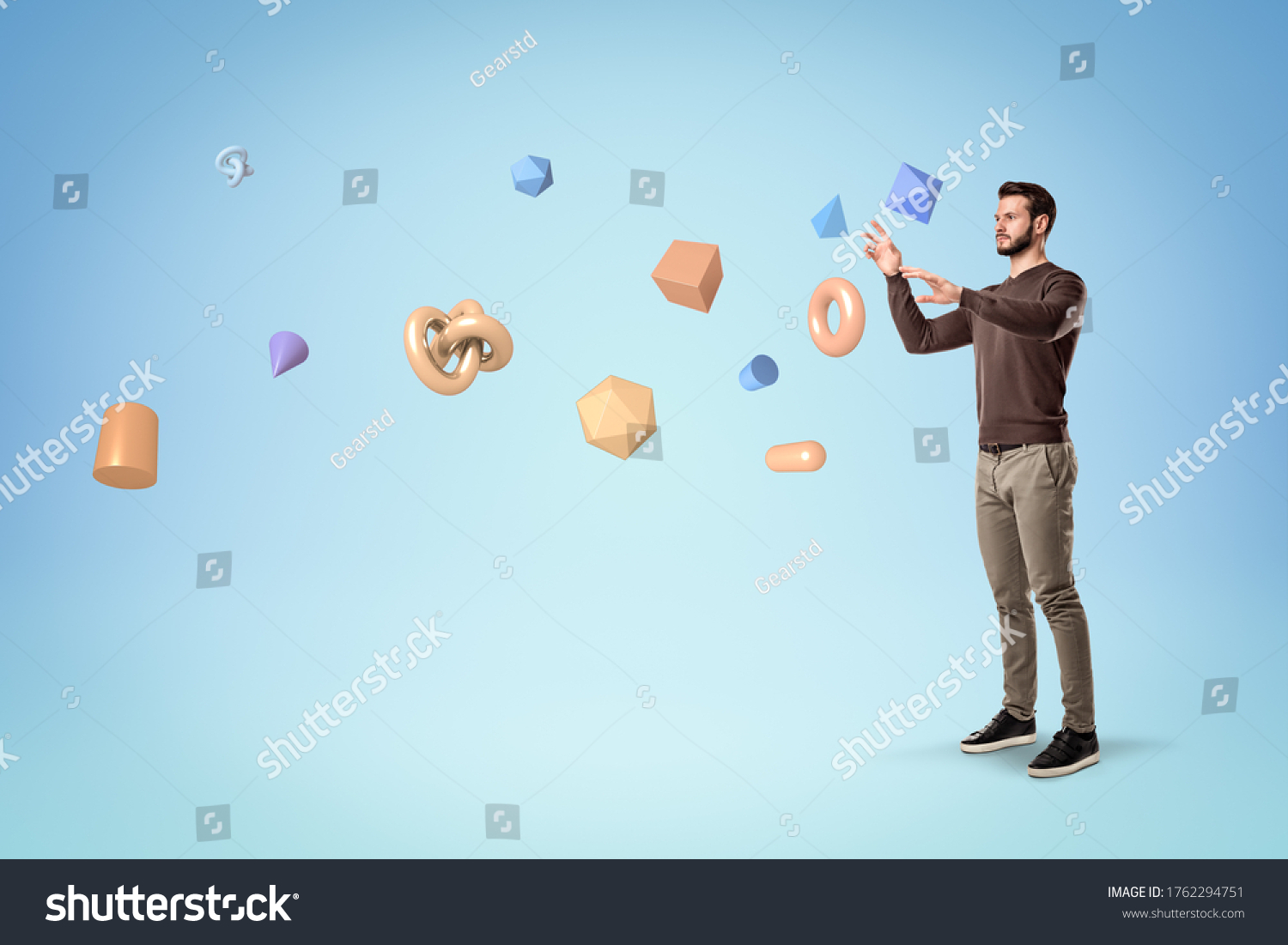 Handsome bearded young man in casual clothes standing and levitating lots of different geometric objects on light blue background. Thinking processes. Imagination and creativity. #1762294751