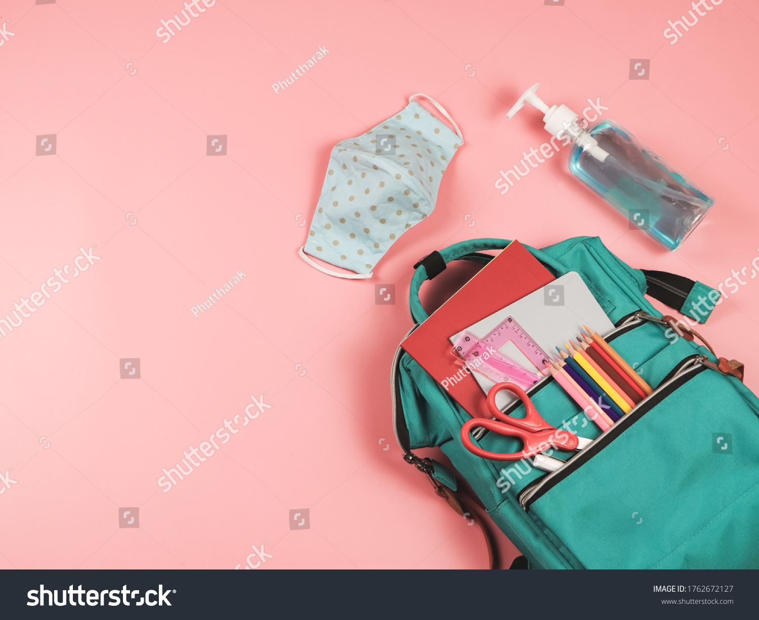 COVID-19 prevention while going back  to school  and new normal  concept.Top view of backpack with school supplies , blue polka dot fabric masks and sanitizer gel on pink background. #1762672127