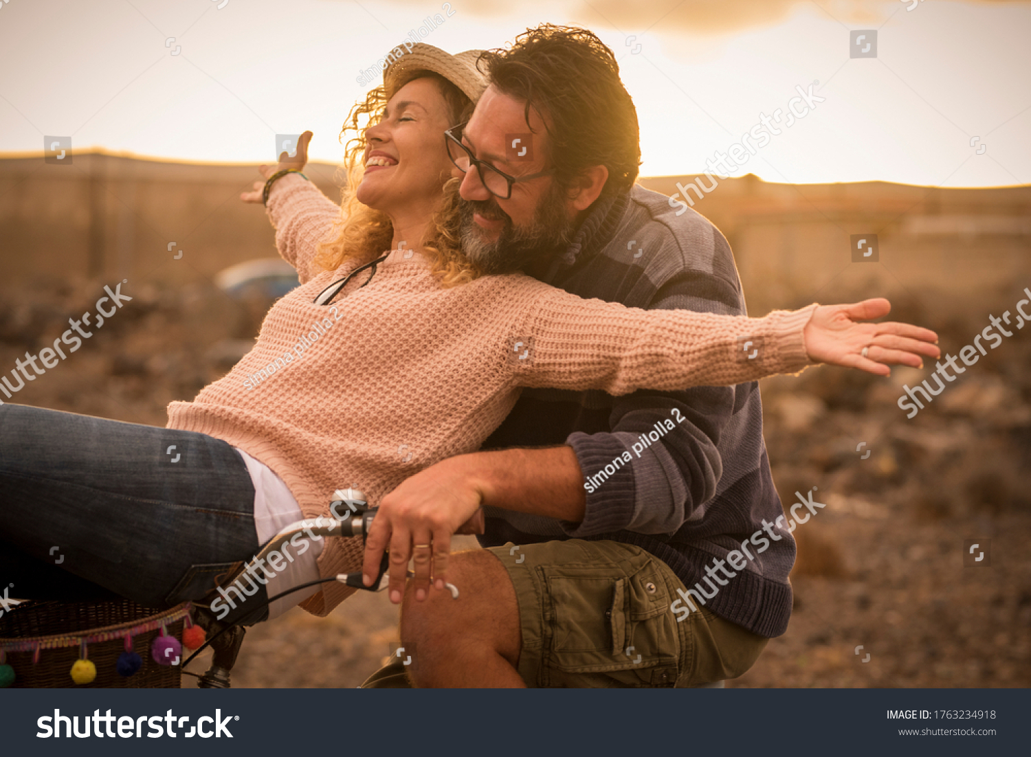 Happy adult people cheerful couple enjoy the outdoor leisure activity riding a bike together man carrying woman and laugh a lot in friendship and relationship - active youthful persons #1763234918