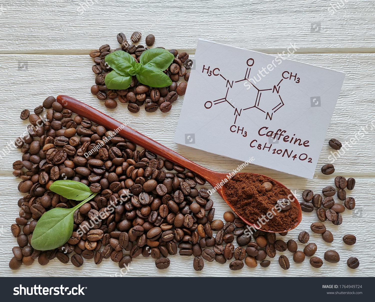 Structural chemical formula of caffeine molecule with roasted coffee beans and wooden spoon filled with coffee powder. Caffeine is a central nervous system stimulant, psychoactive drug molecule. #1764949724