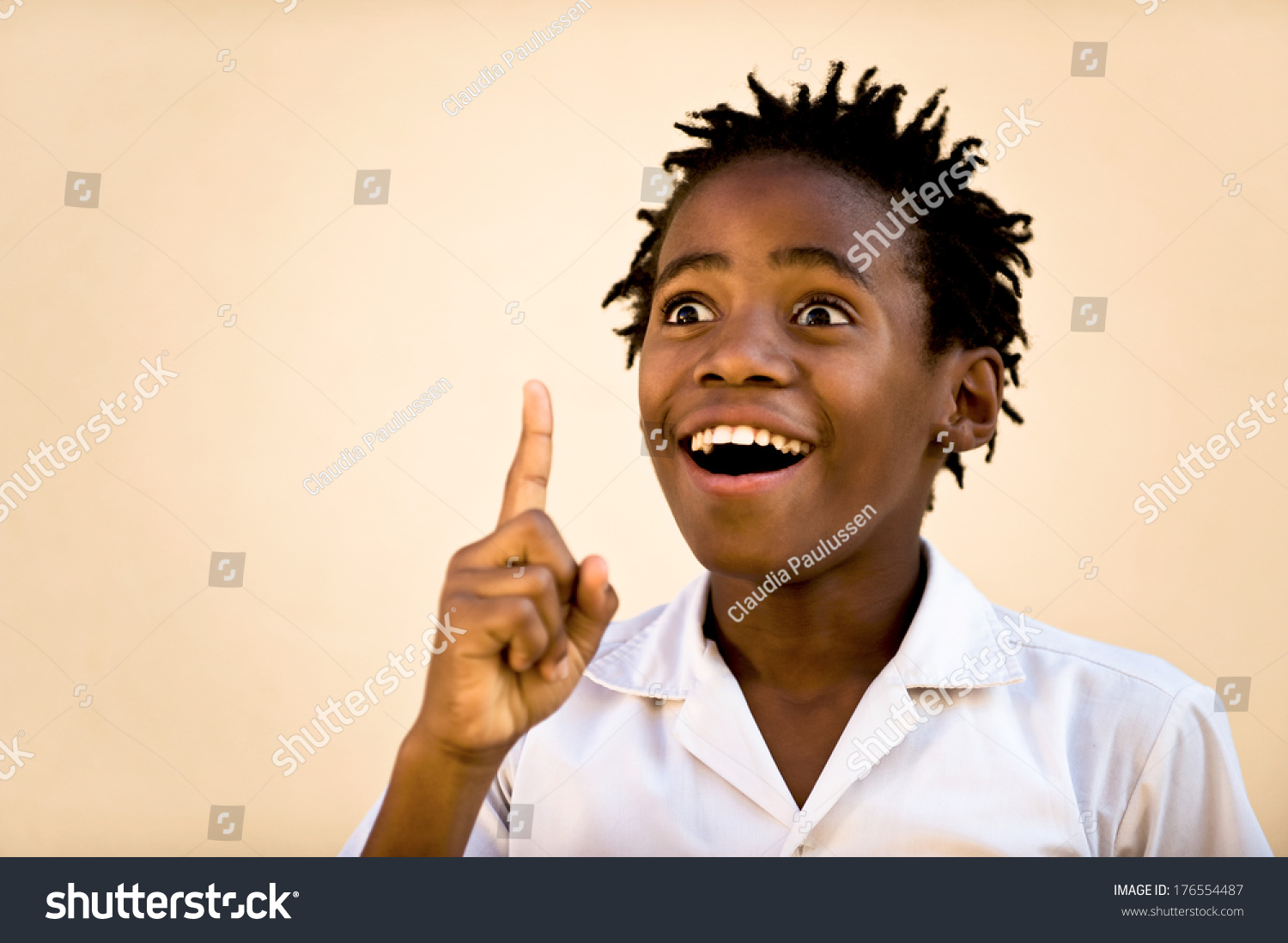 An African boy pointing his finger upwards looking excited. #176554487